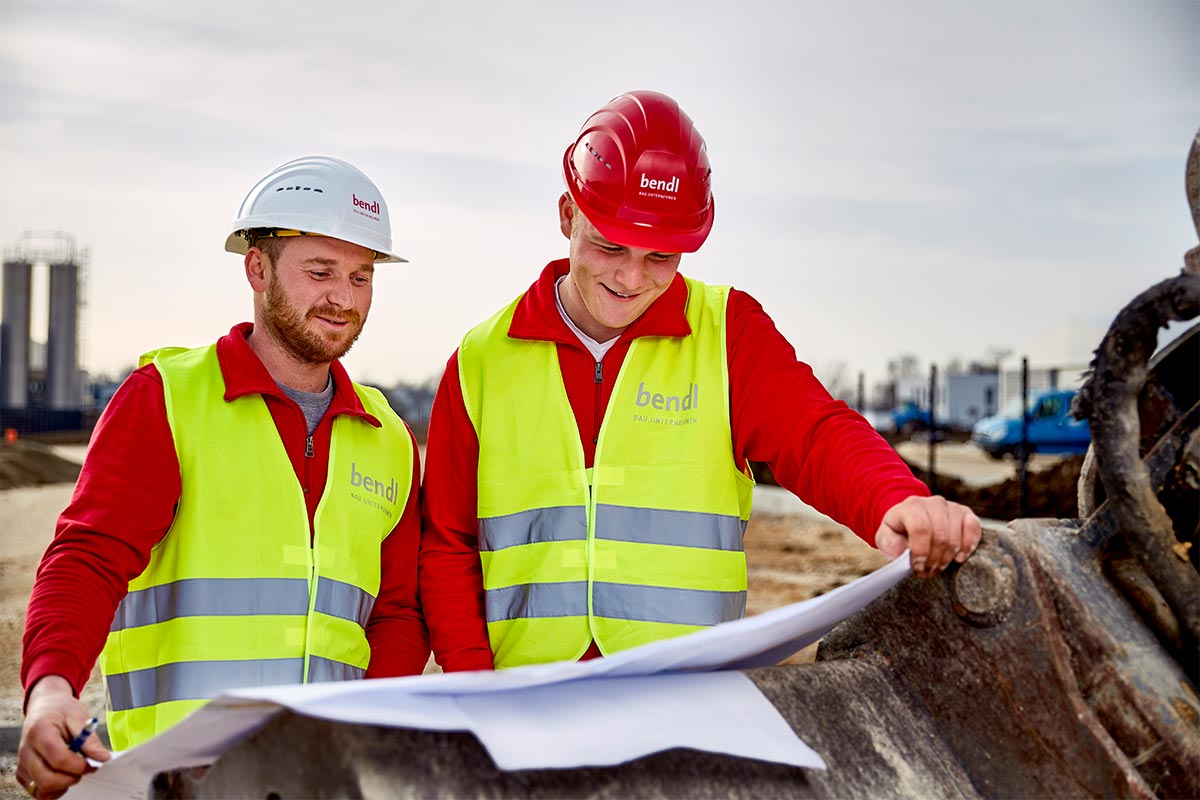 Auszubildender Marcel und Polier Martin besprechen den Grundrissplan.